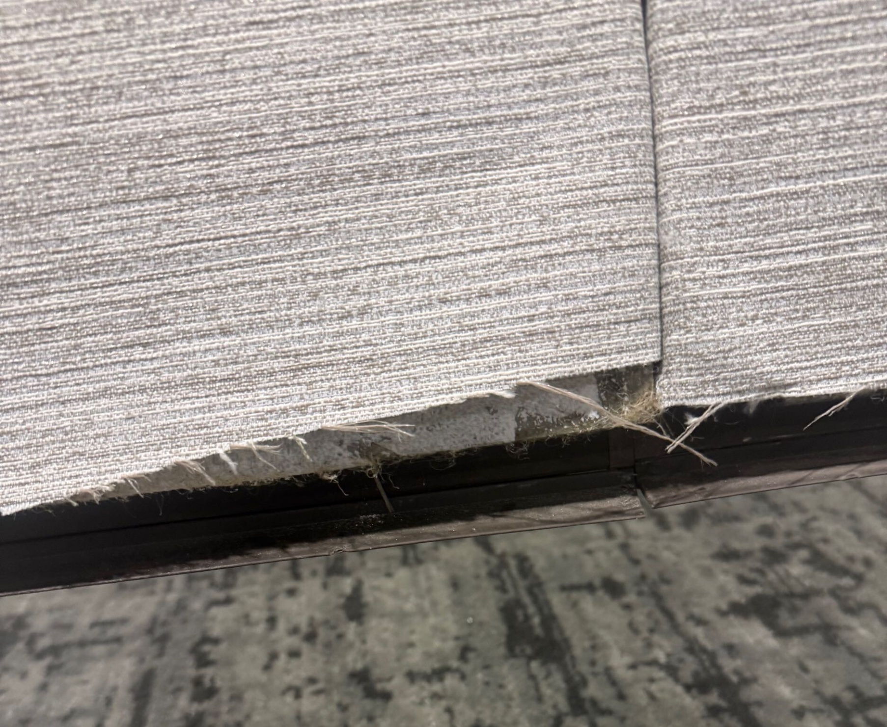 Bottom of operable wall panel with an exposed face because the wallcovering was cut too short.